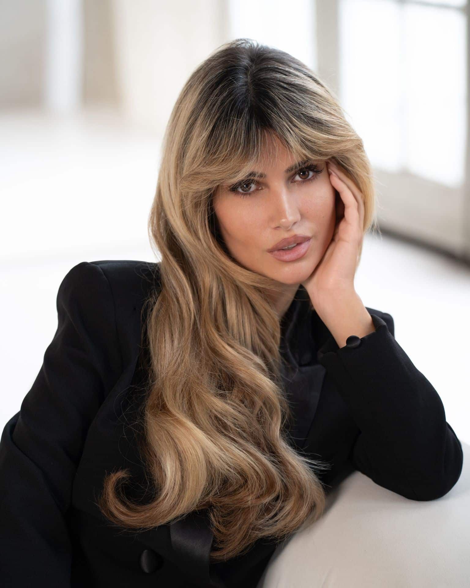 Frau mit langen dunkelblonden Haaren mit einer HAnd im Gesicht